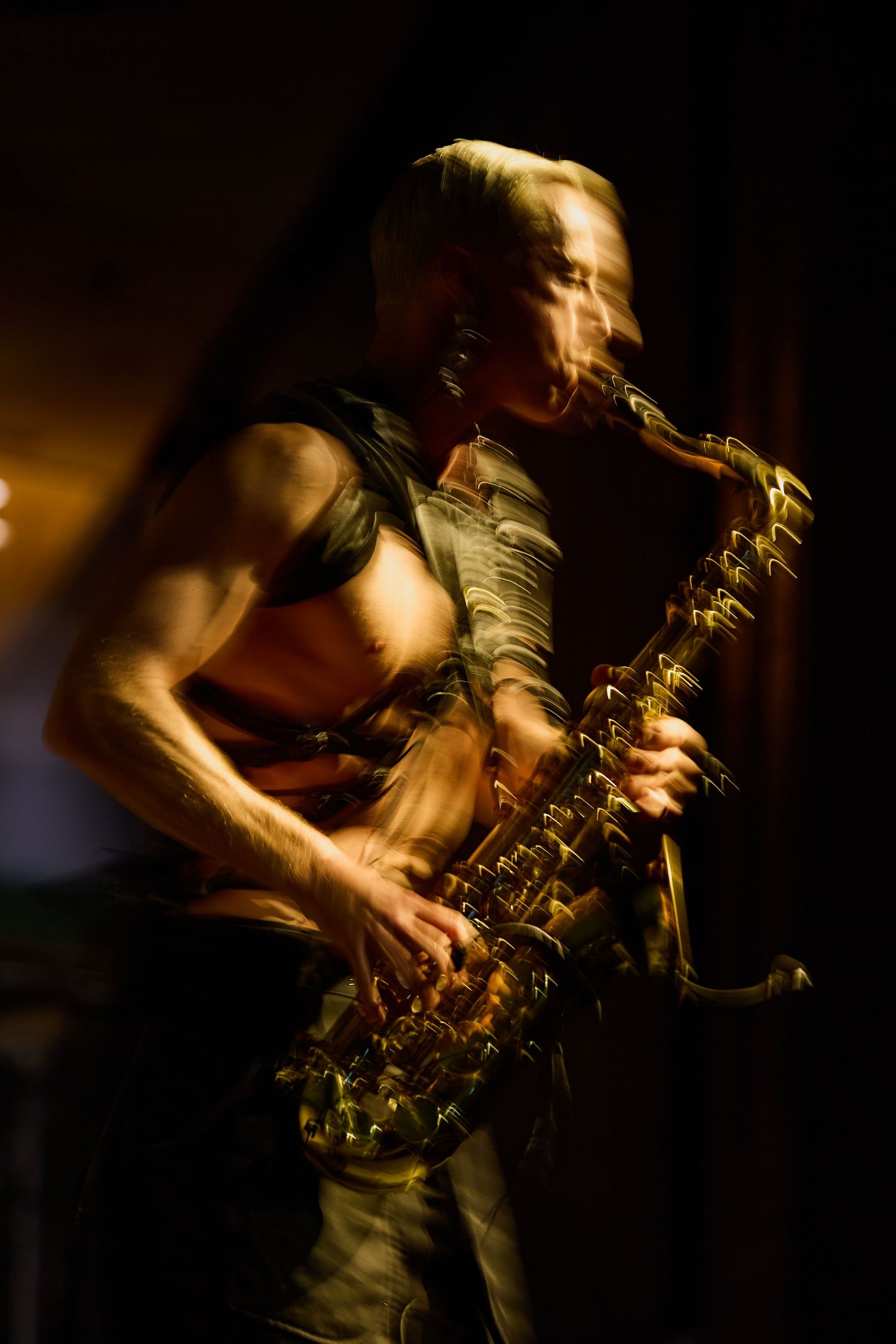 Motion blur artistic photo of saxophonist performing on stage in dramatic golden light.