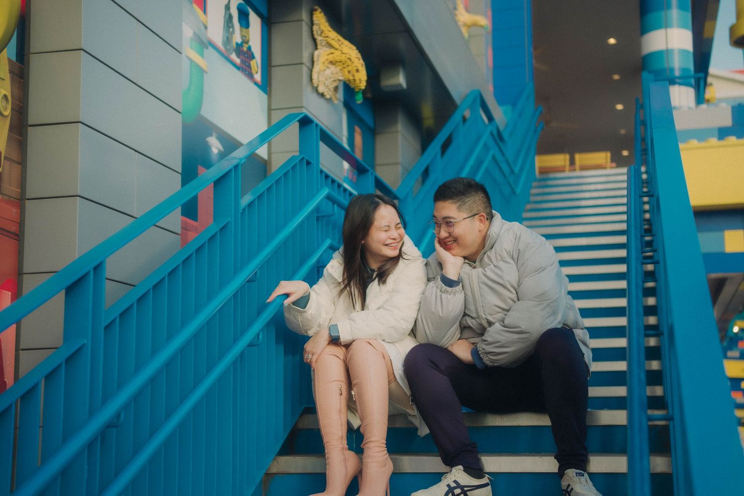 Couple sitting on colorful blue stairs sharing a joyful moment.