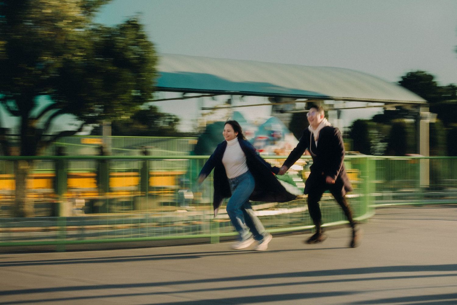 Couple running playfully through a sunny outdoor park together.