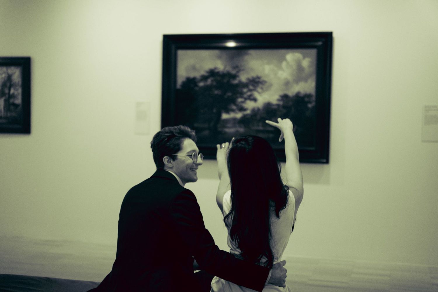 Couple sharing a moment while viewing landscape painting in art gallery.