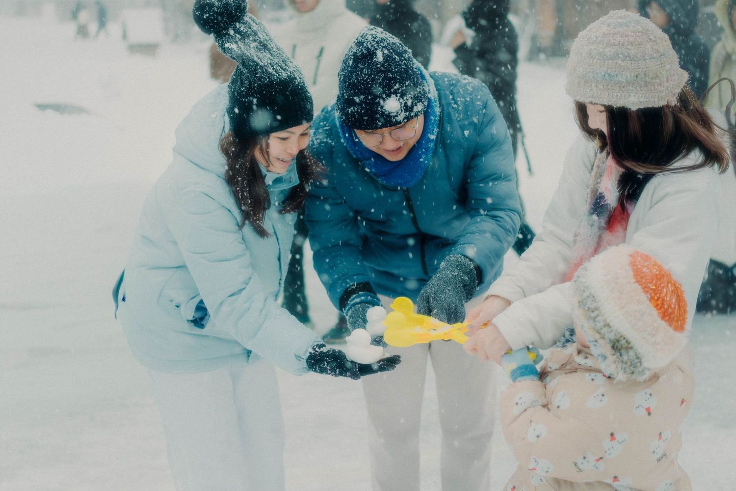 Group of friends playing with snow tools in winter snowfall.