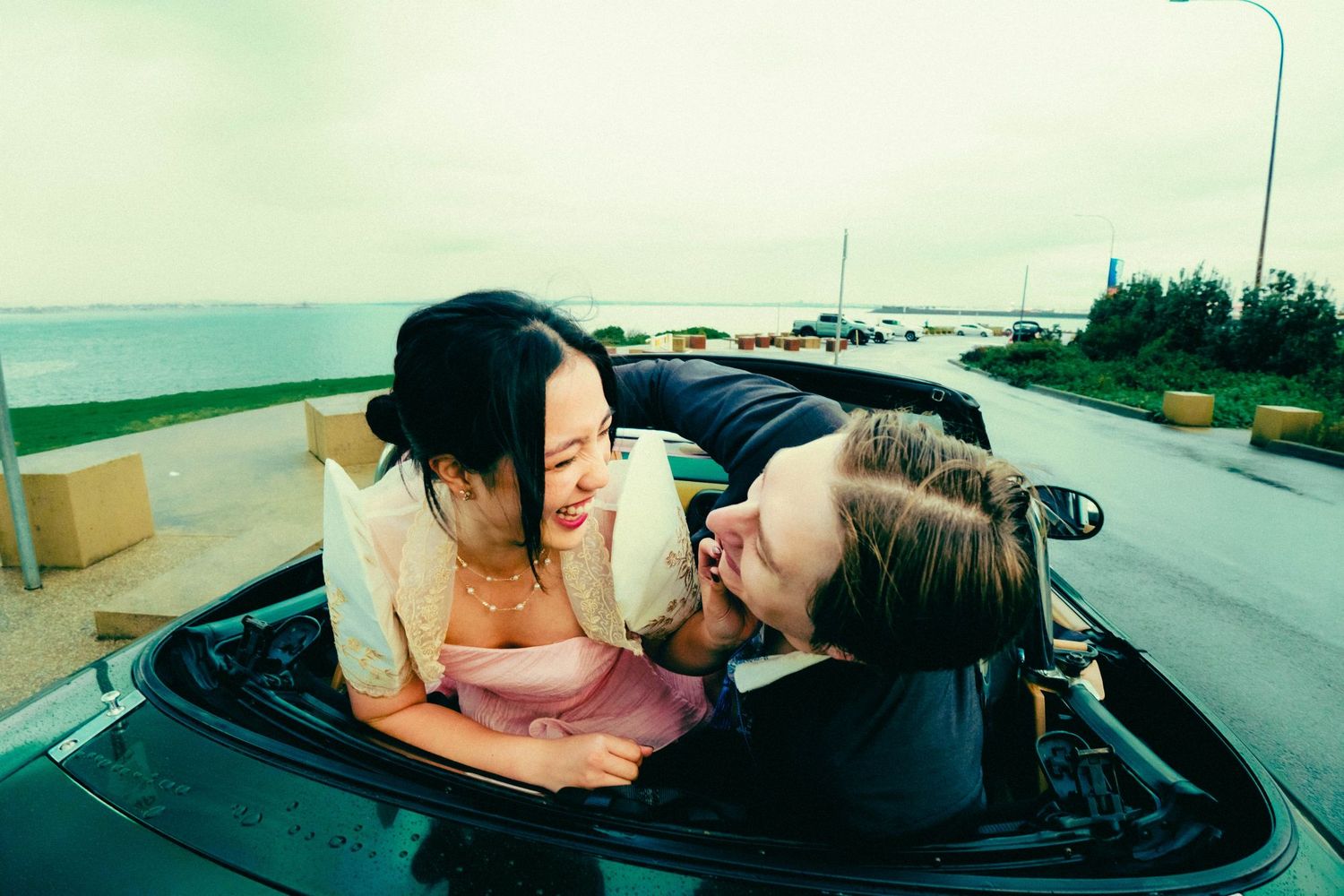 Couple sharing a romantic moment in a convertible car parked by the ocean.