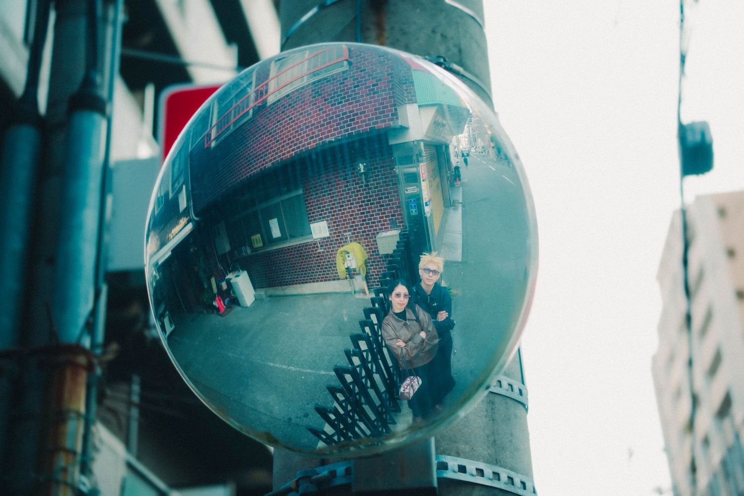 Couple reflected in a convex street mirror in urban setting.