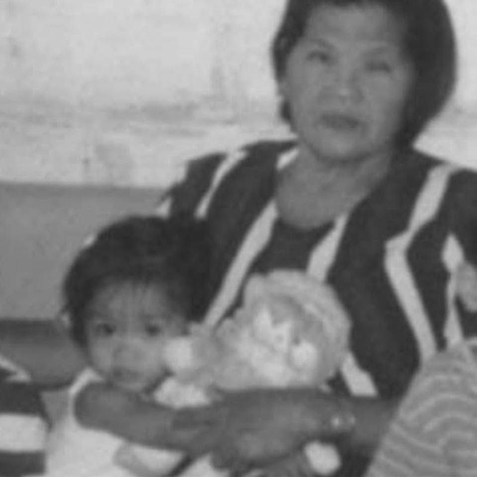 Vintage black and white photo of an elderly woman holding a young child with a stuffed toy.