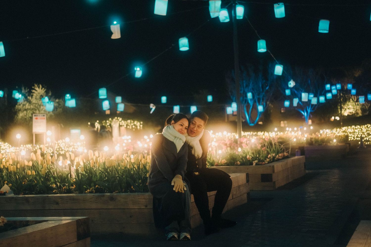 Romantic couple sitting under glowing lanterns at night festival.