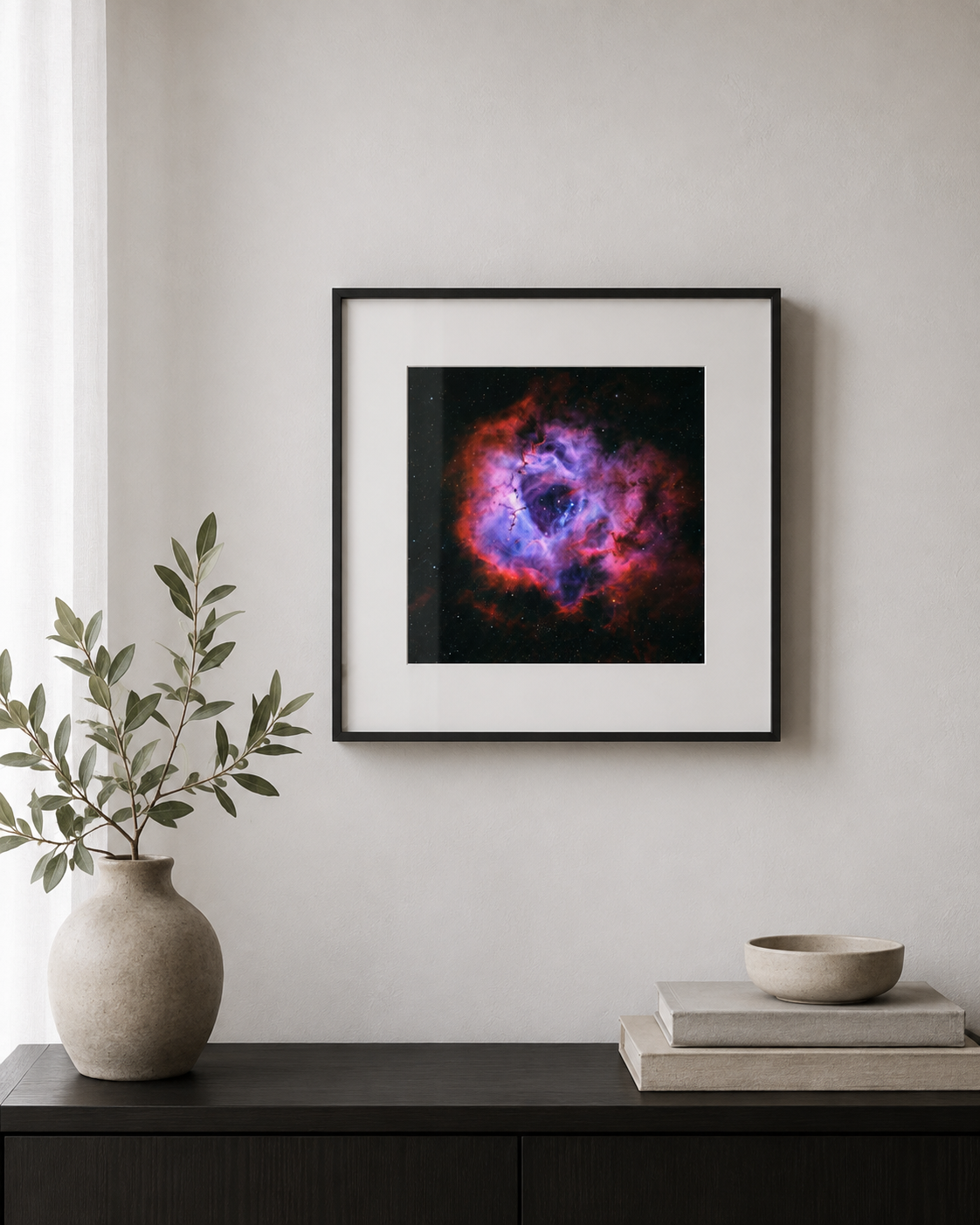 Framed Rosette Nebula print with vibrant red, blue, and purple hues displayed on a wall above a dark console table.