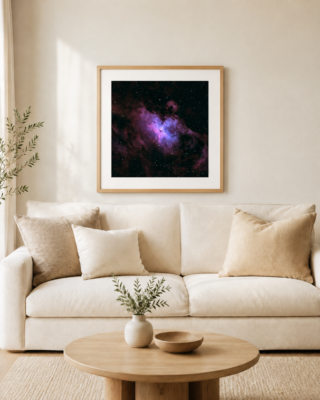 Framed purple nebula galaxy art print hanging above a cream sofa with beige pillows in a modern minimalist living room.