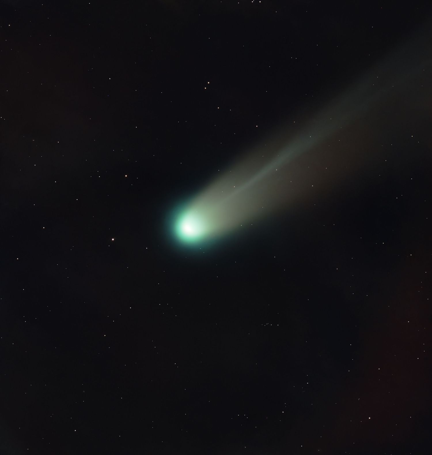 A bright green comet with a glowing tail streaking across a dark starry night sky.