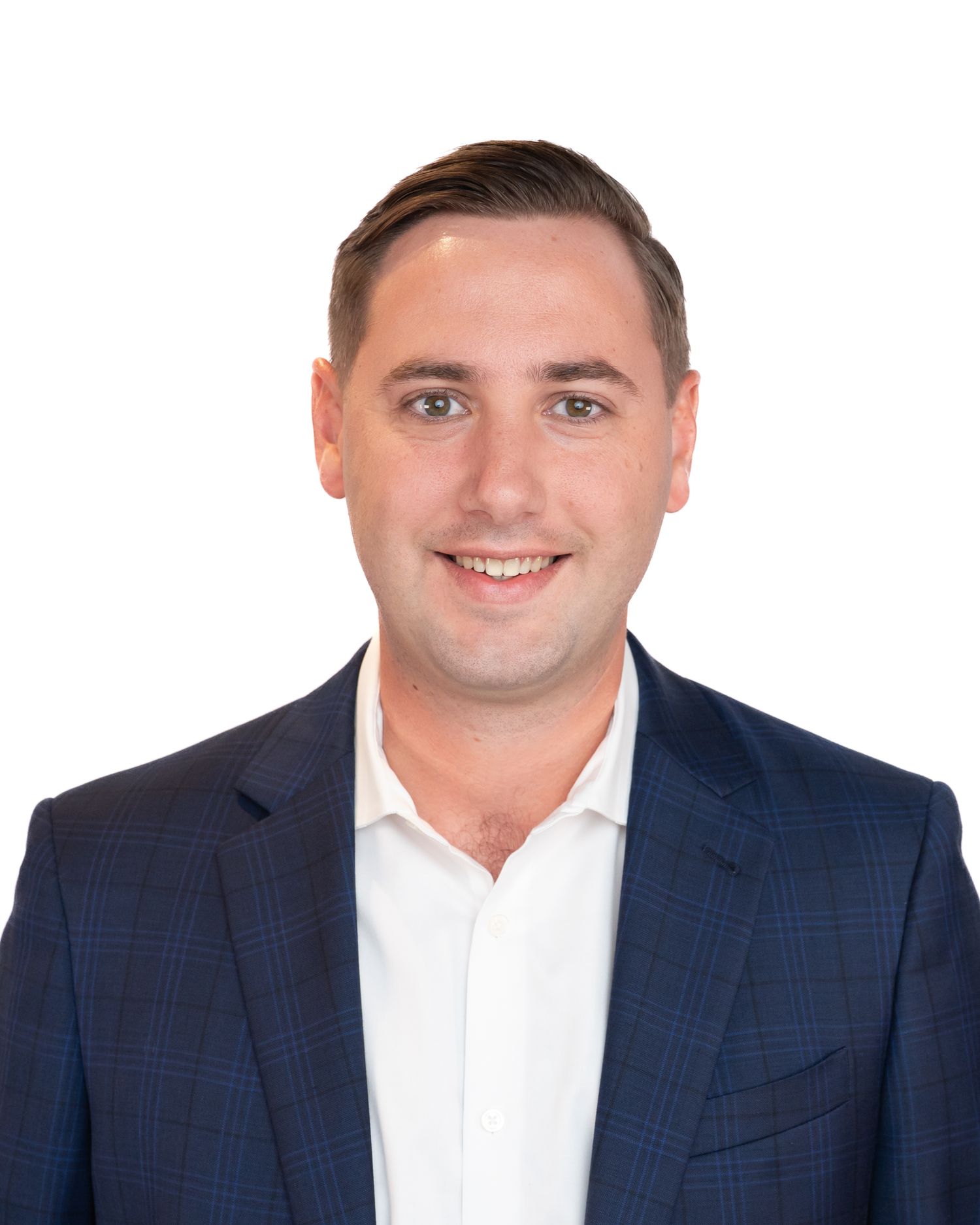 Professional headshot of a smiling young man in a navy blazer and white shirt against a white background.