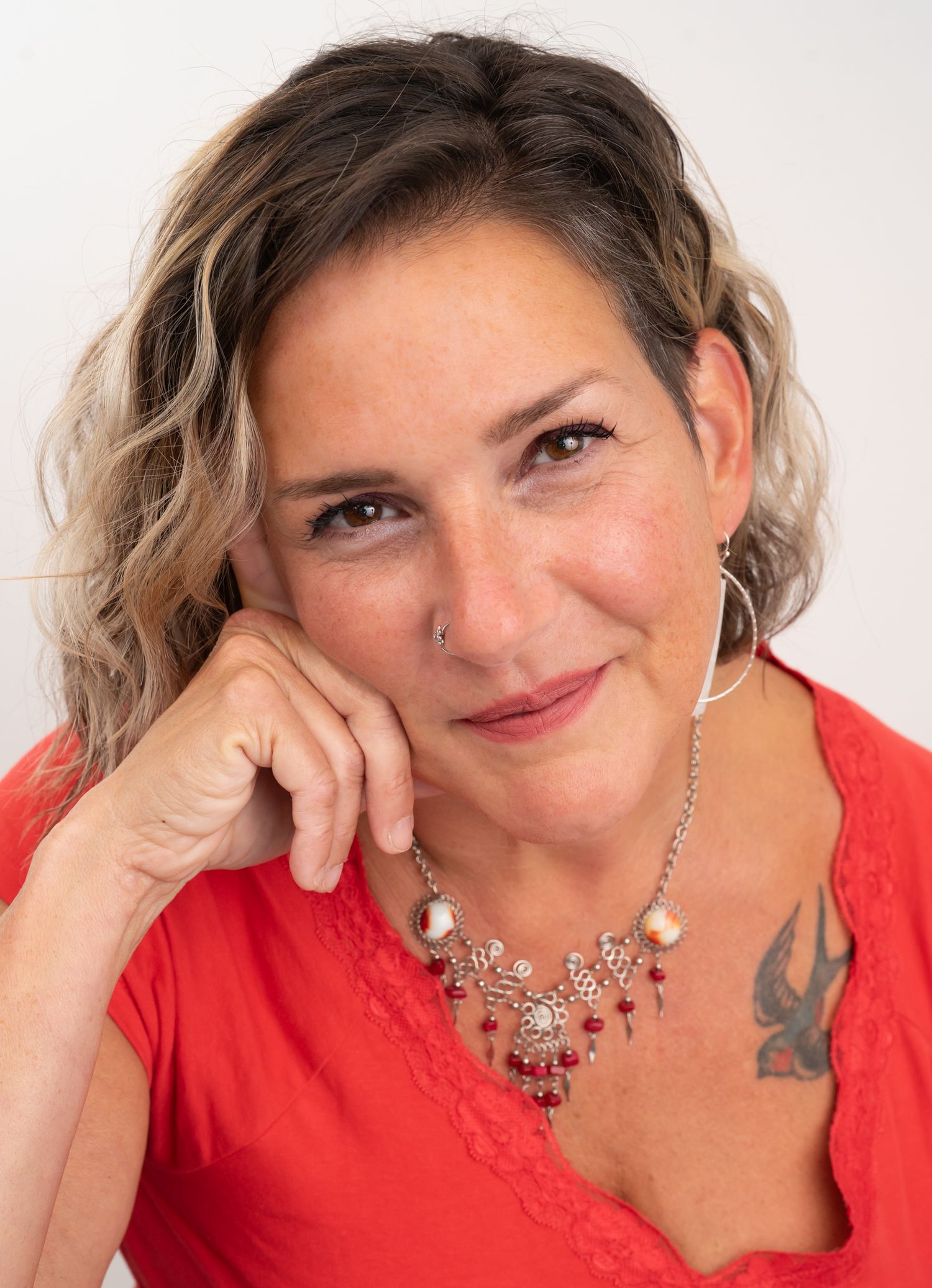 Portrait series of someone in a red top with jewelry against a white background.