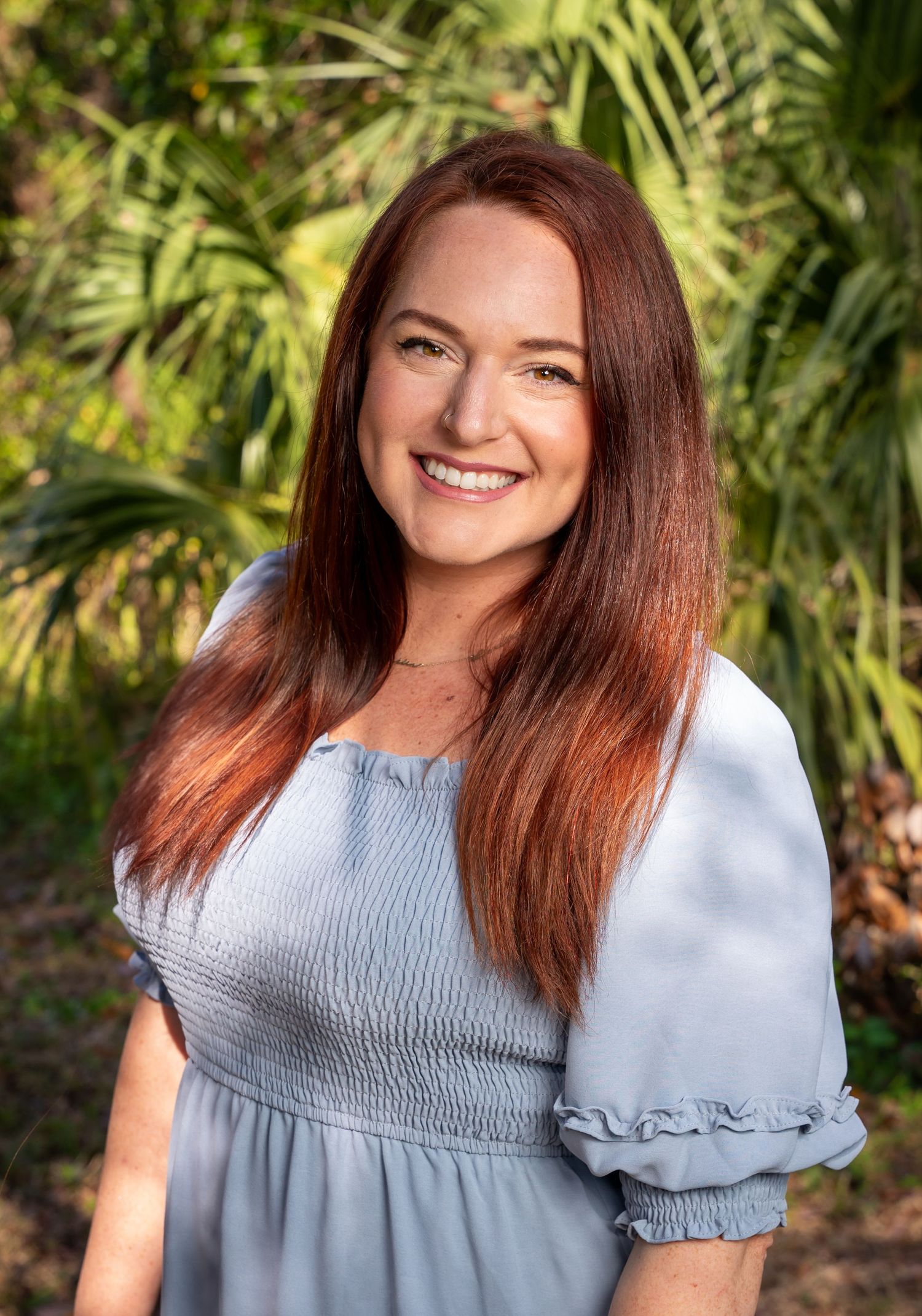 Professional portrait series in a garden setting with soft lighting and a light blue smocked blouse.