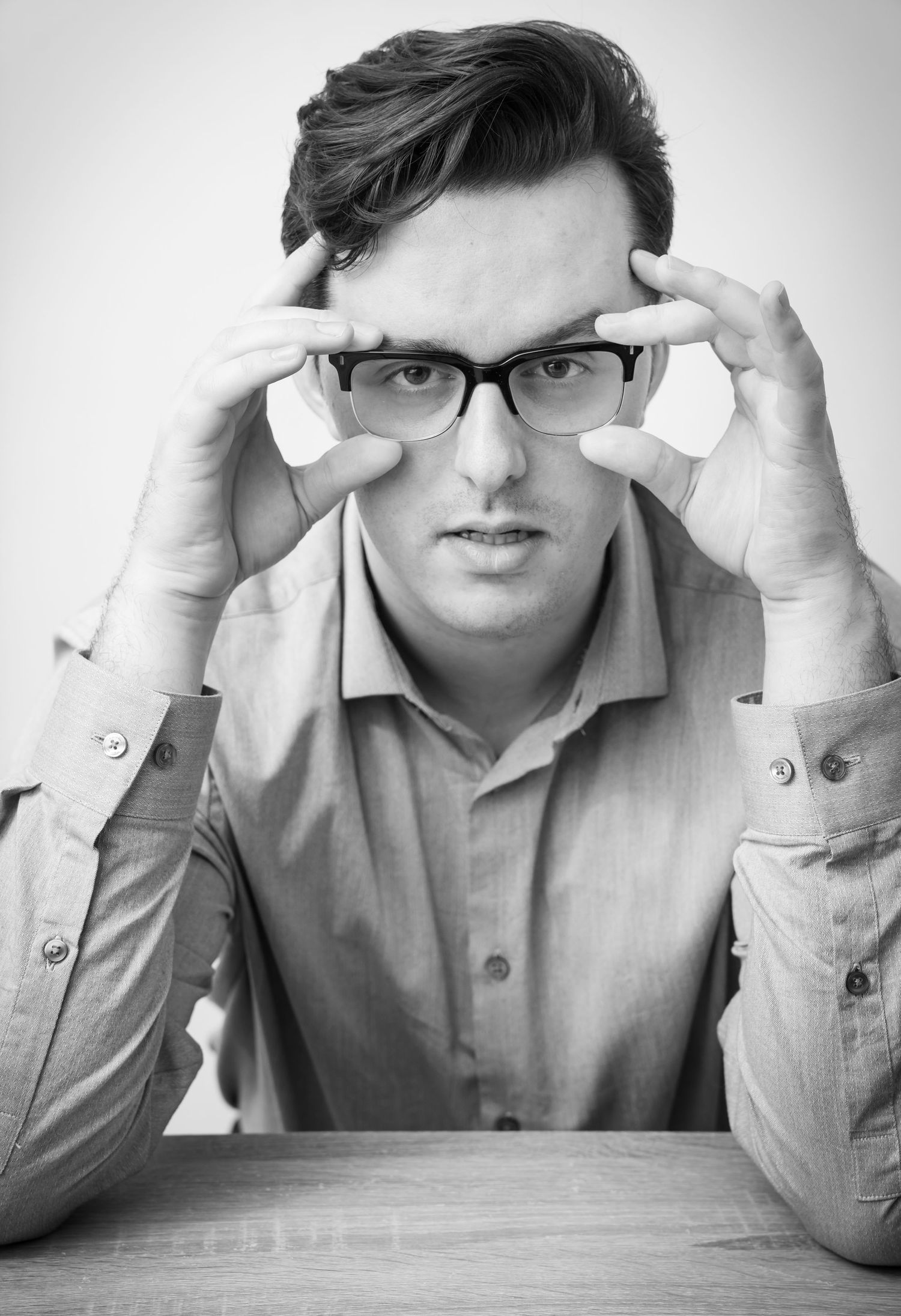 Black and white photo sequence showing frustration through hand gestures at a wooden desk.