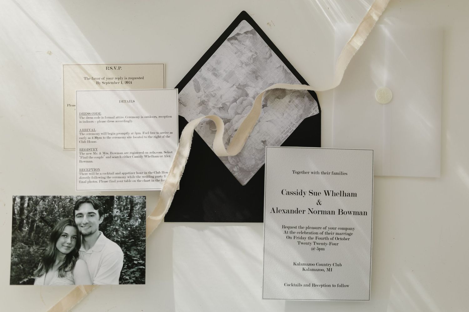 Wedding invitations and documents arranged artistically with black and white engagement photo.