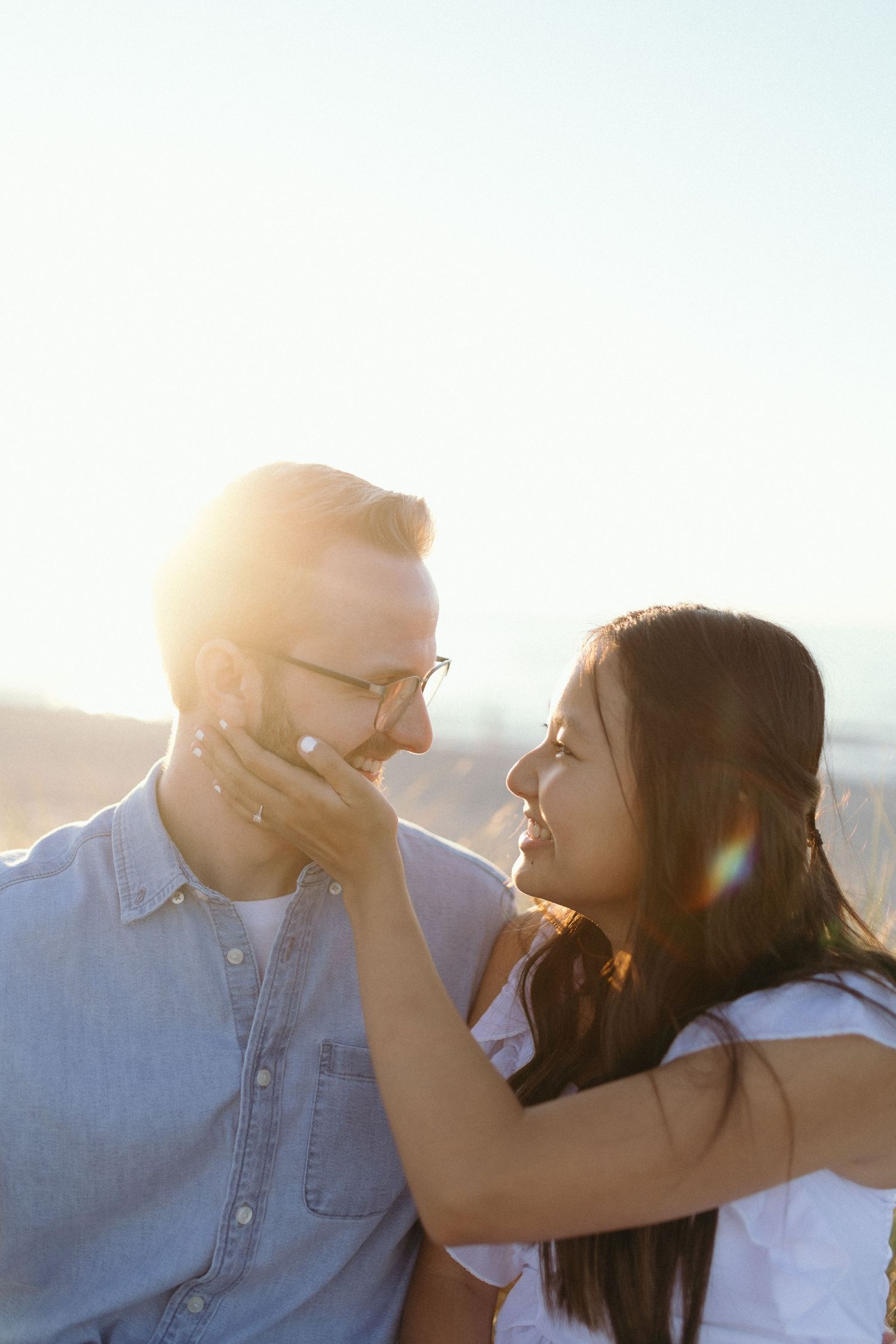 Intimate couple moment captured in warm sunlight with lens flare.