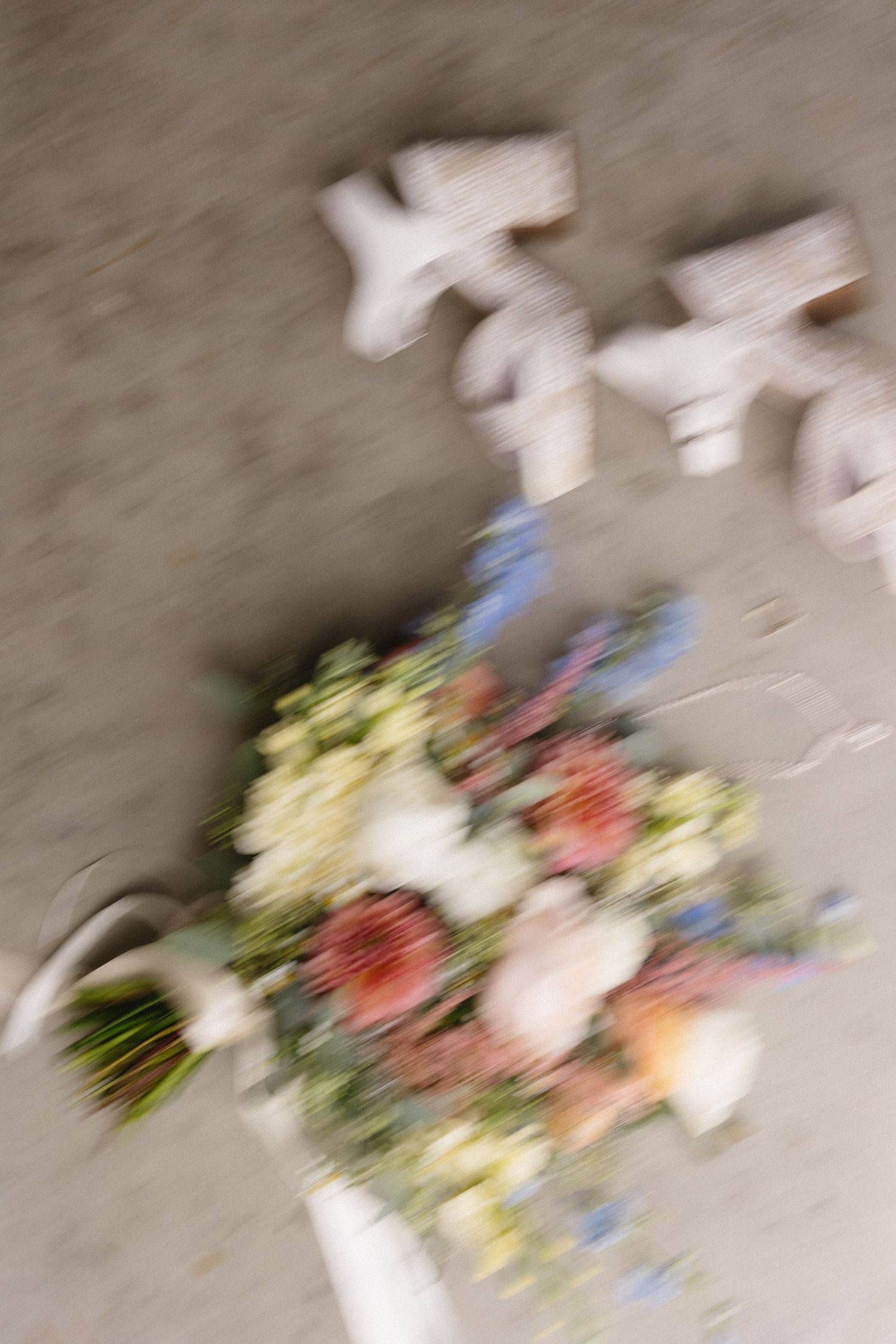 Artistic blurred photo of a wedding bouquet with colorful flowers against neutral background.