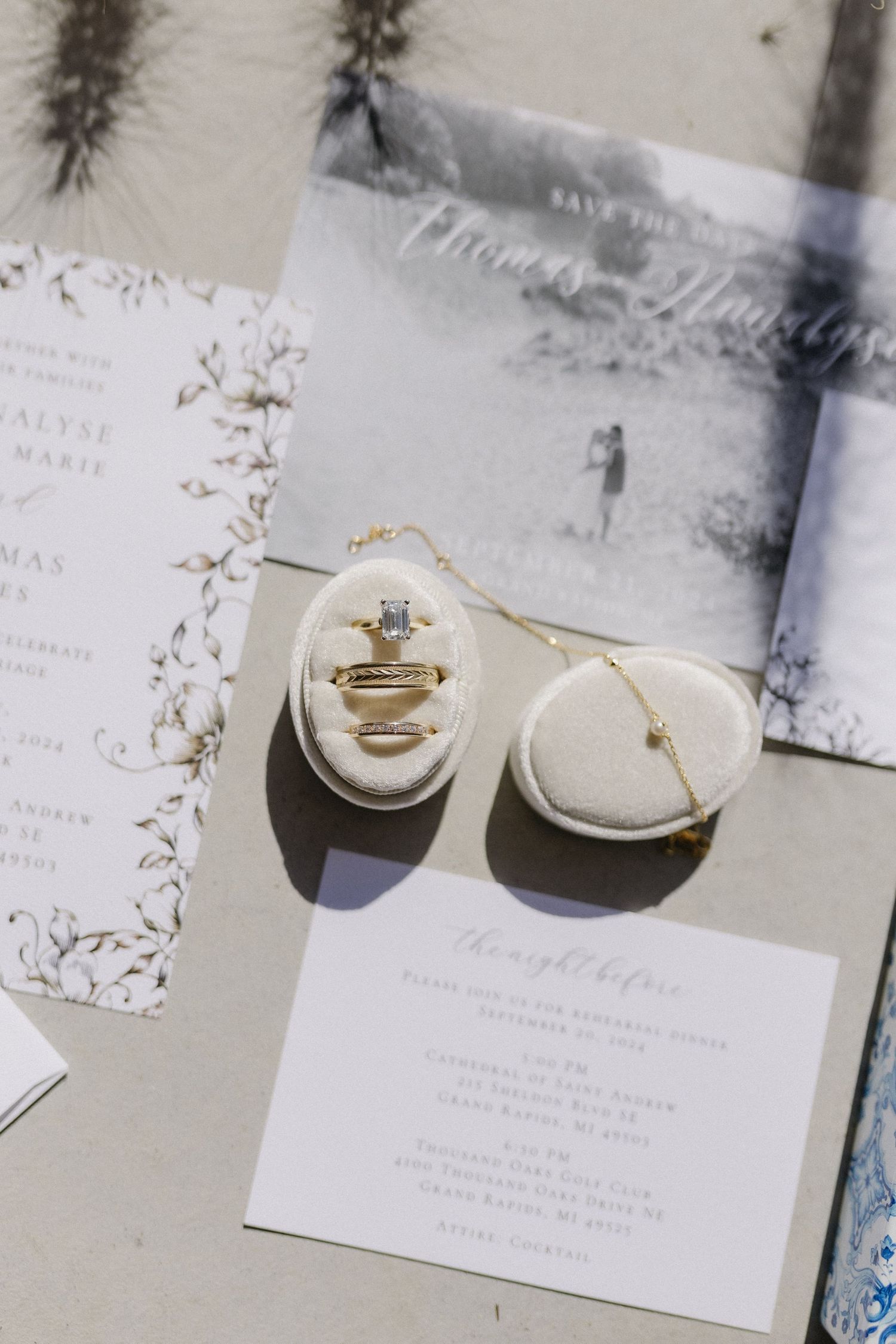 Wedding rings and invitation details artistically arranged on a light surface with floral elements.