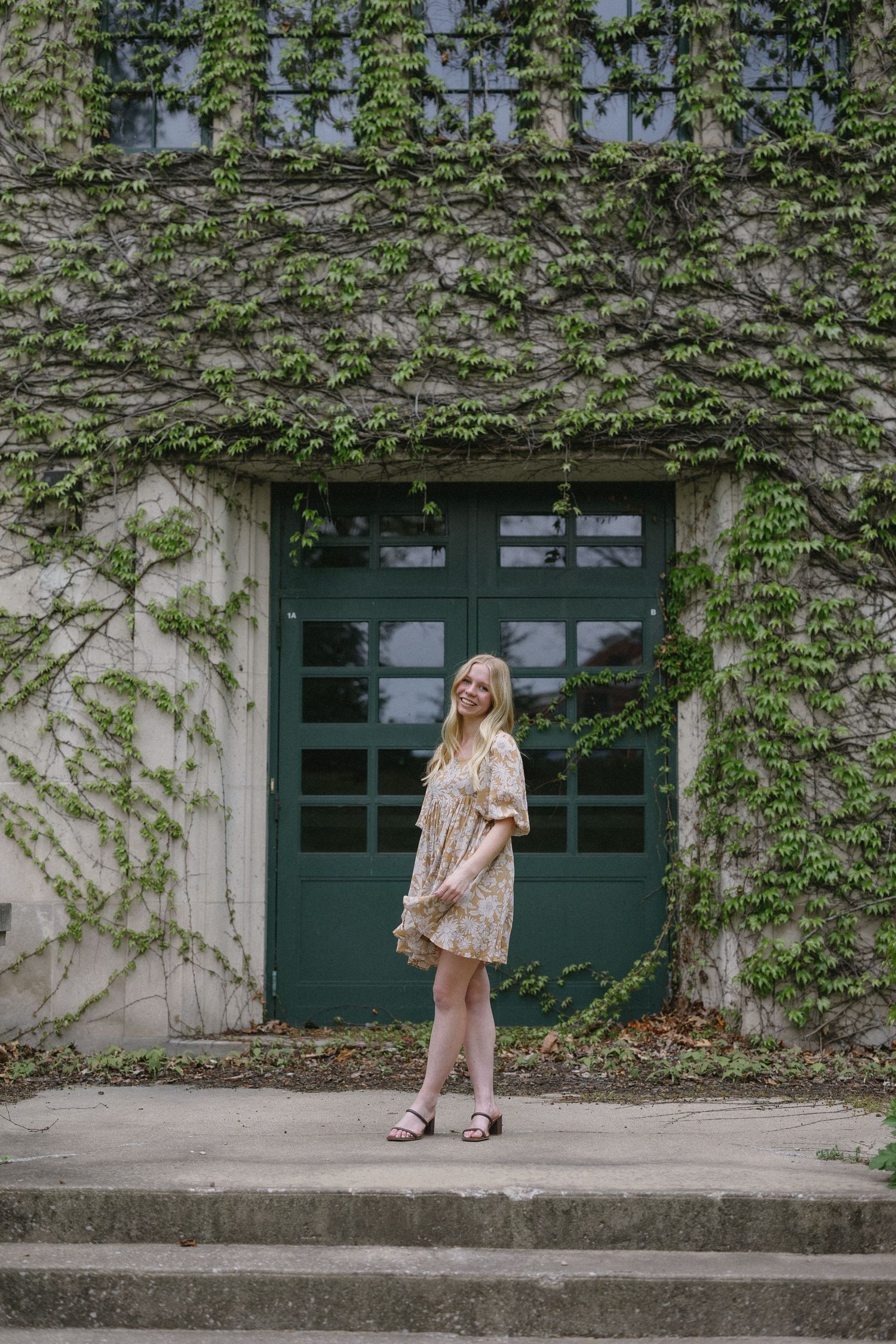 A series of four outdoor shots showing someone in a floral dress and sandals posing against an ivy-covered wall.