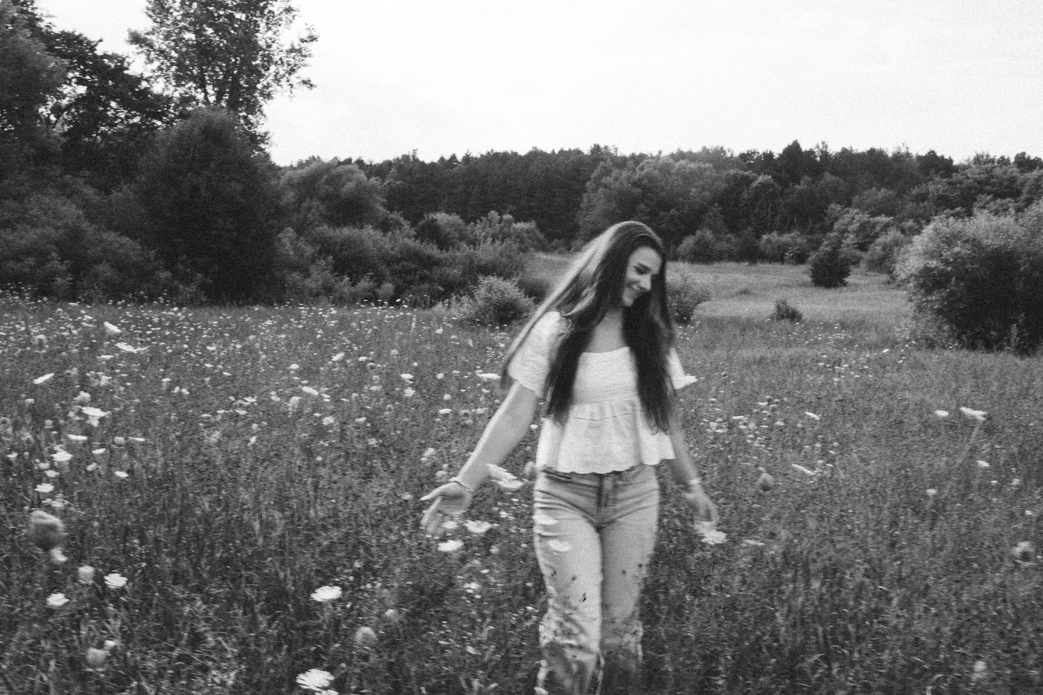 A couple walks hand in hand through a dreamy wildflower meadow in black and white.