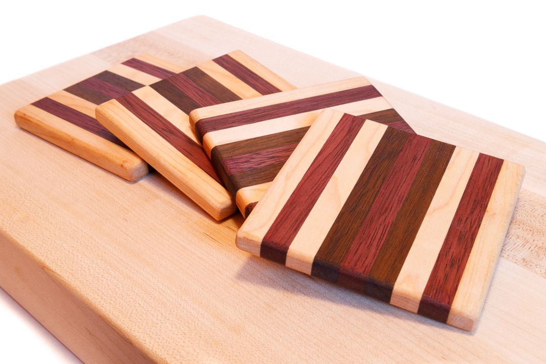 A set of wooden coasters made from strips of maple, purple heart, and walnut wood.