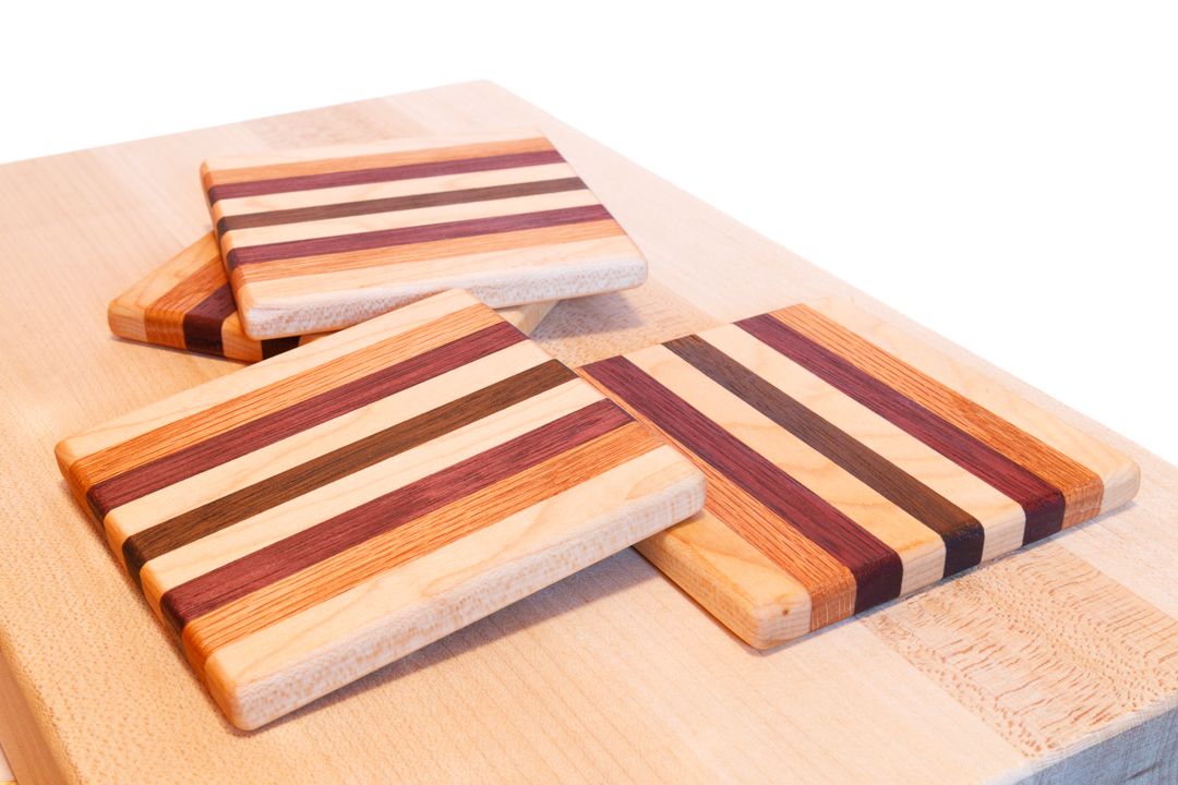 A set of wooden coasters made from strips of maple, red oak, purple heart, and walnut wood.