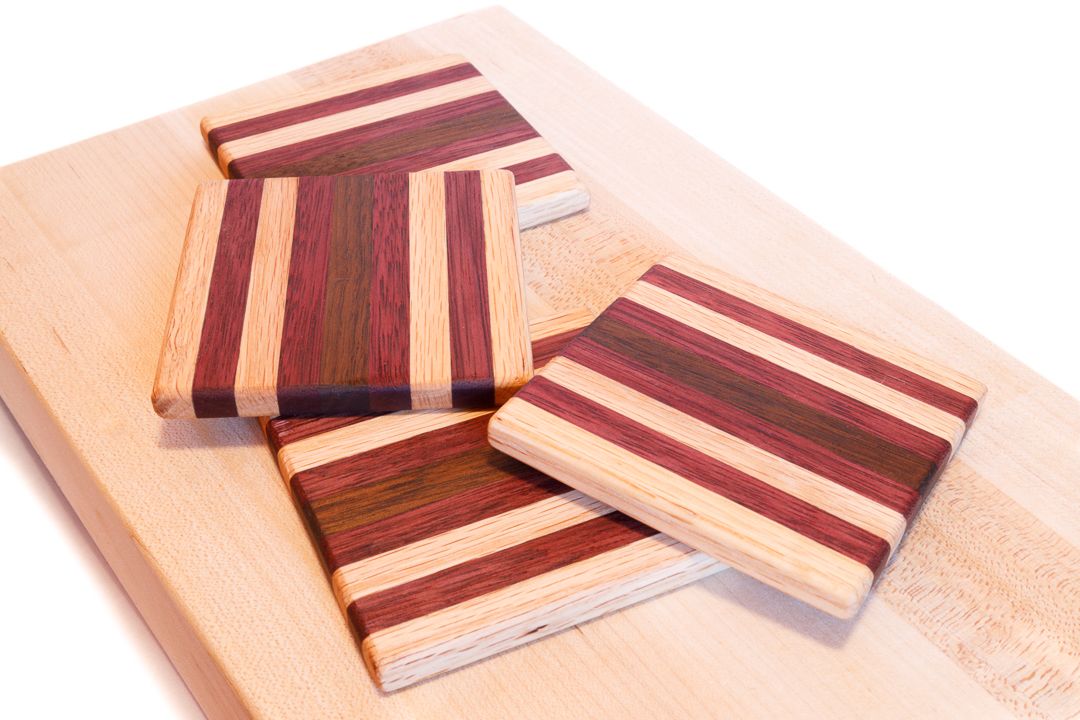 A set of wooden coasters made from strips of red oak, purple heart, and walnut wood.