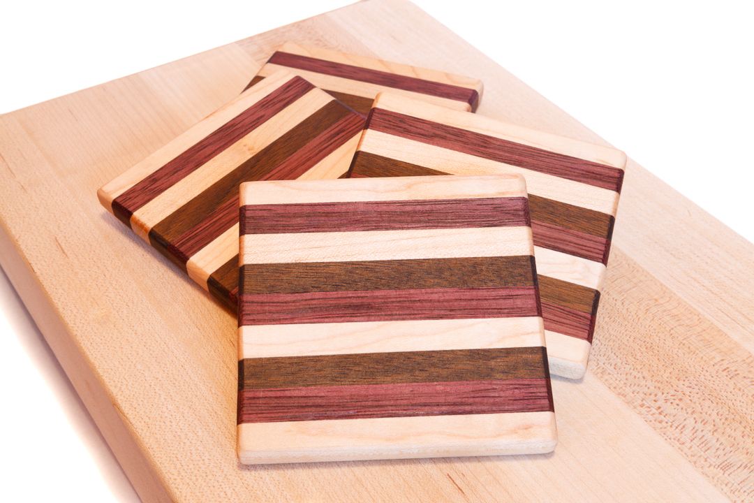 A set of wooden coasters made from strips of maple, purple heart, and walnut wood.