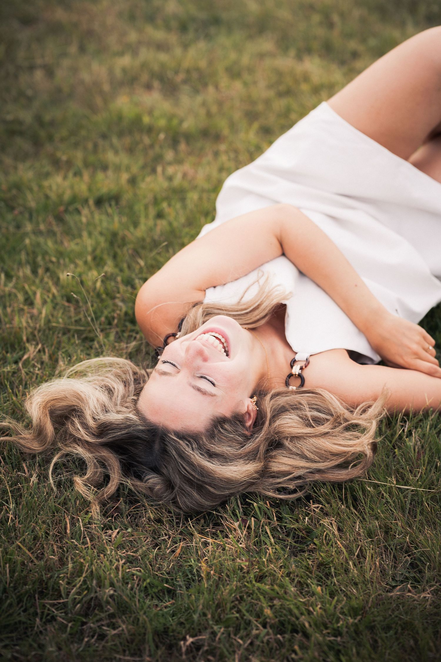 Femme blonde heureuse allongée sur l'herbe verte