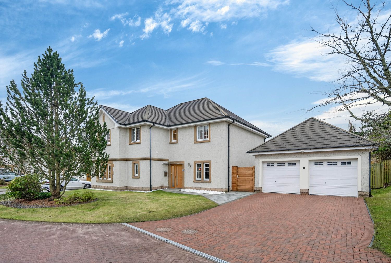 Exterior view of modern home with brick driveway and attached garage under blue sky.
