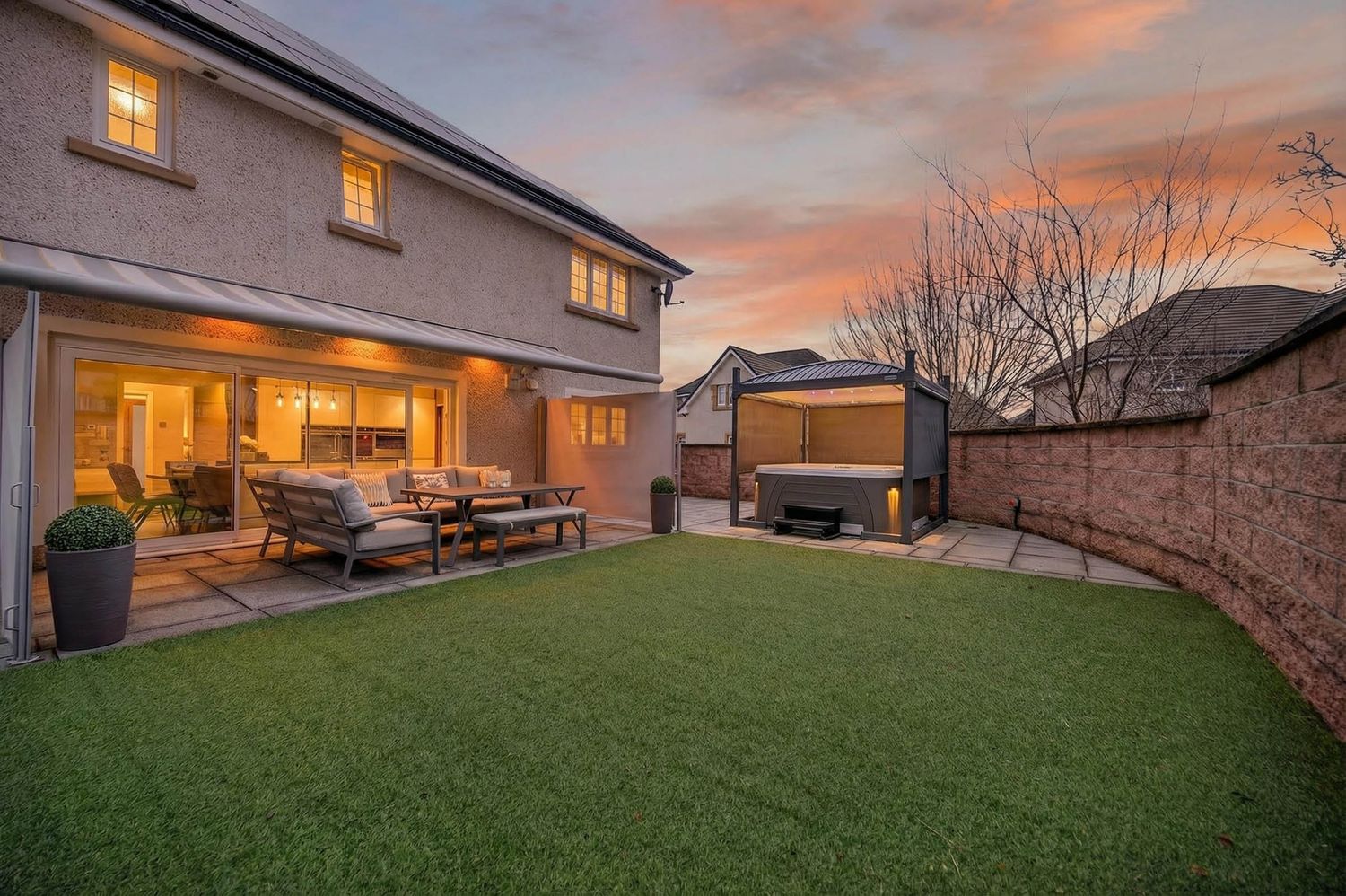 Dusk view of residential home with warm interior lighting and manicured lawn.