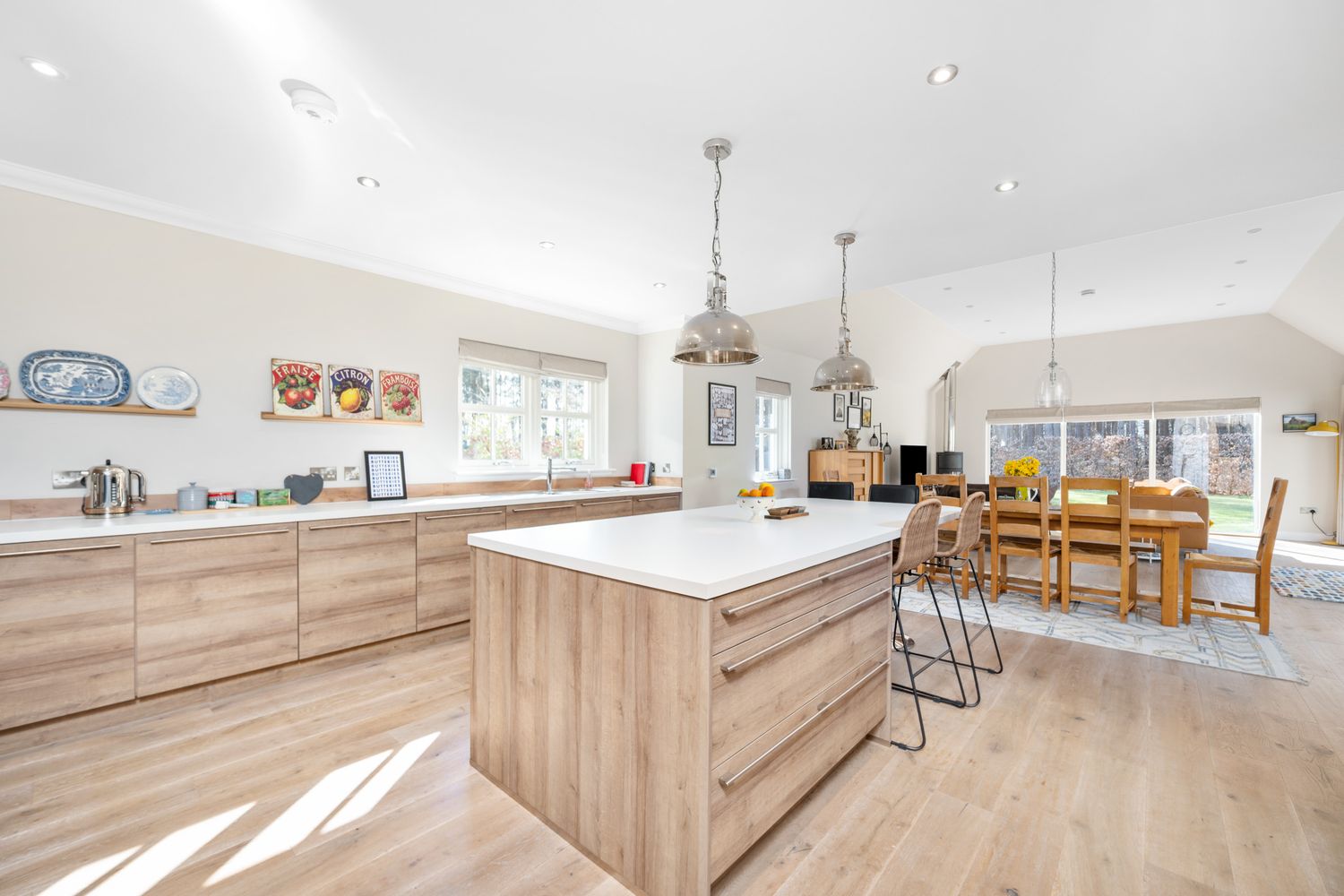 Bright open concept kitchen with light wood cabinets, center island, and dining area in natural sunlight.
