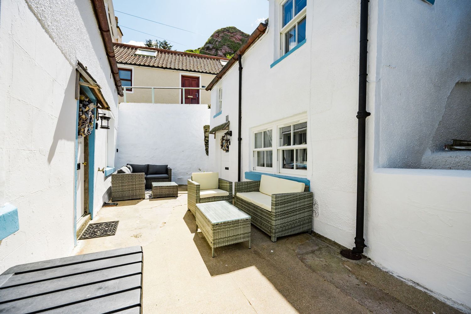 White patio courtyard with modern outdoor furniture and blue accents between whitewashed Mediterranean style buildings.