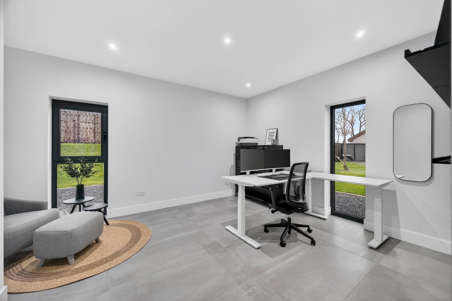Modern home office setup with grey walls, desk, and framed artwork.