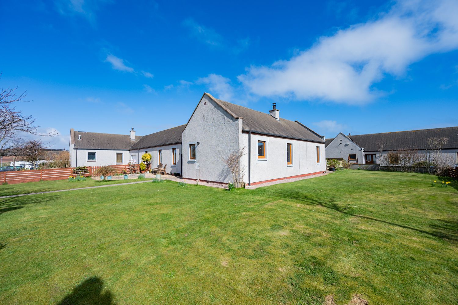White single-story bungalow with well-maintained green lawn under bright blue sky on sunny day.