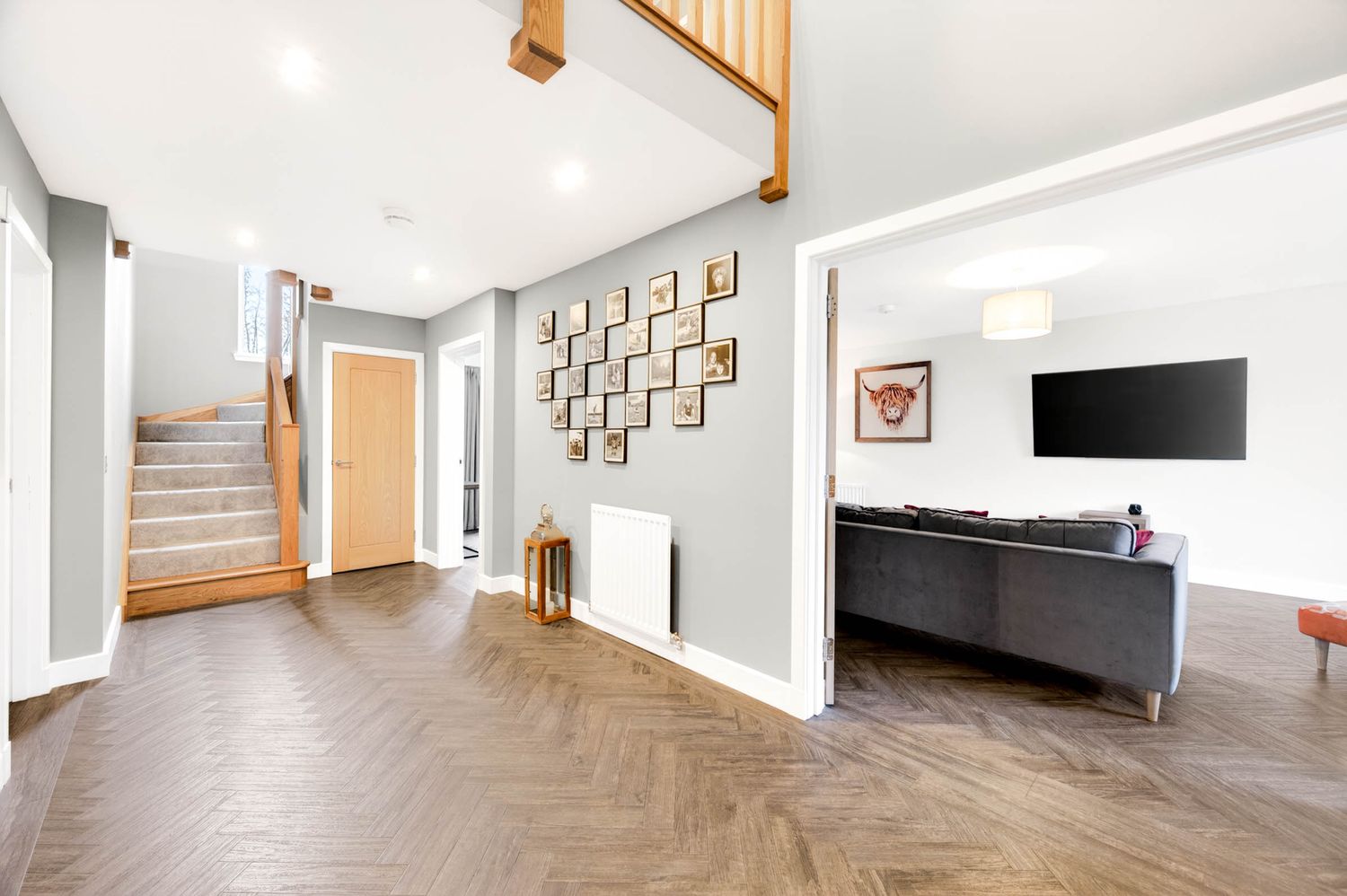 Light-filled hallway with wooden staircase, white walls, and hardwood flooring in contemporary style.