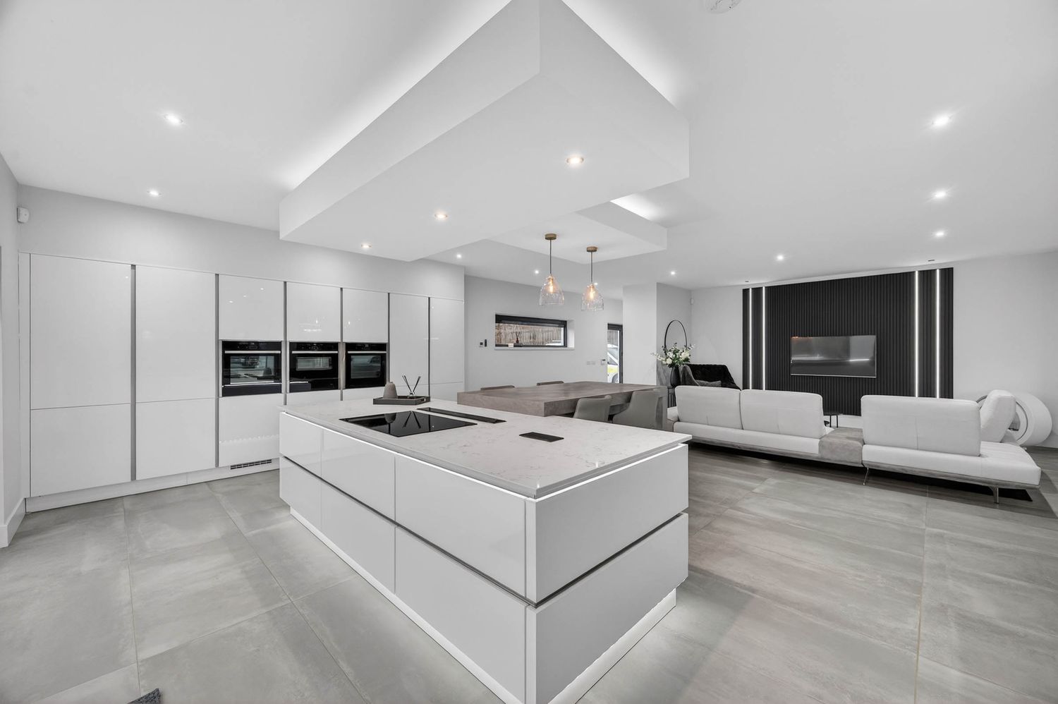 Modern white and gray kitchen with integrated appliances and floating entertainment center.