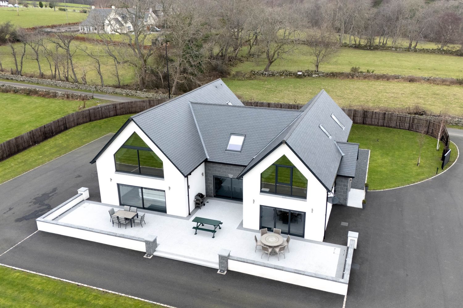 Contemporary white house with angular roof design and expansive patio viewed from above.