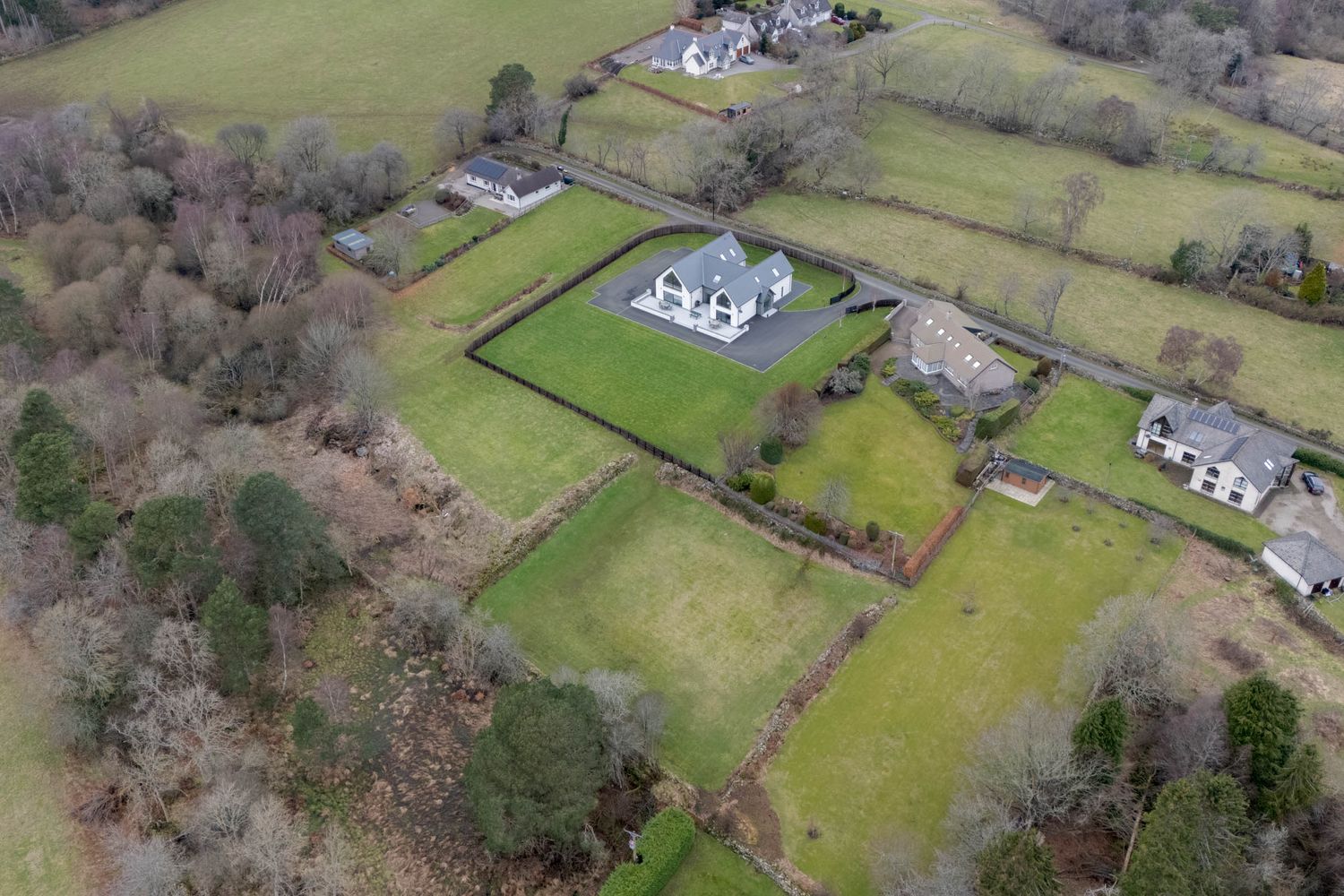 Aerial view of rolling green countryside with scattered white houses and stone walls dividing pastoral fields.