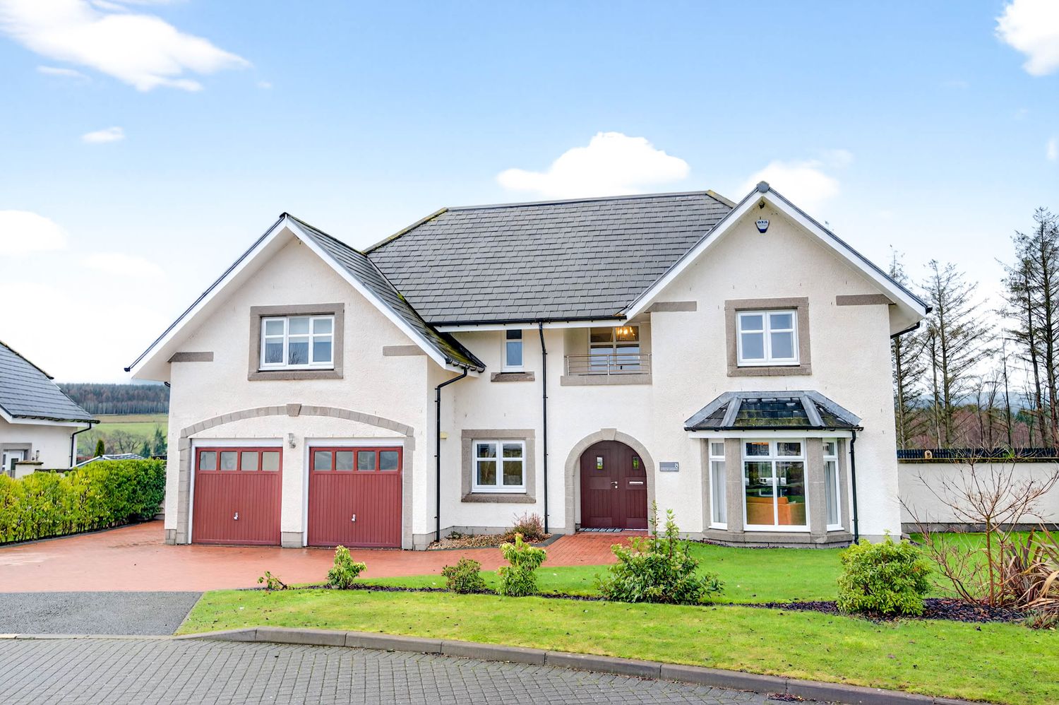 Elegant cream-colored two-story home with red double garage doors and landscaped front yard.