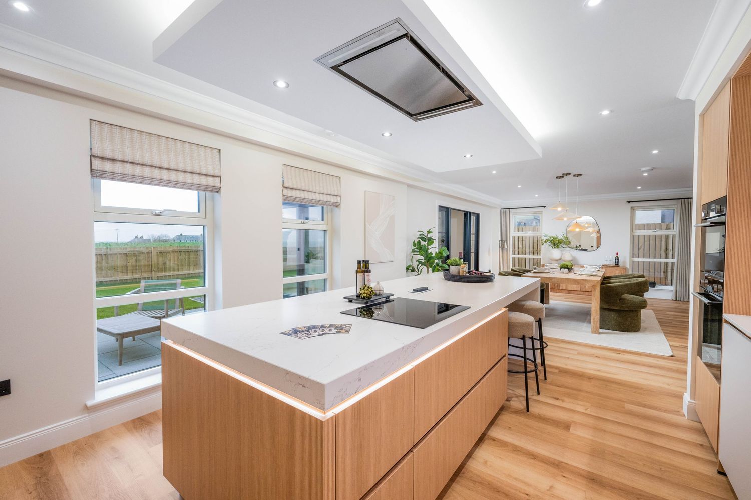 Sleek modern kitchen featuring wood cabinetry, white countertops, and stainless steel appliances.