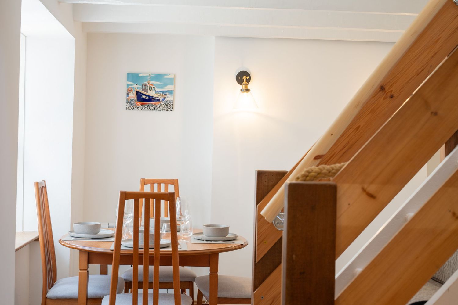Cozy dining area with wooden furniture and white walls under sloped ceiling with natural light.