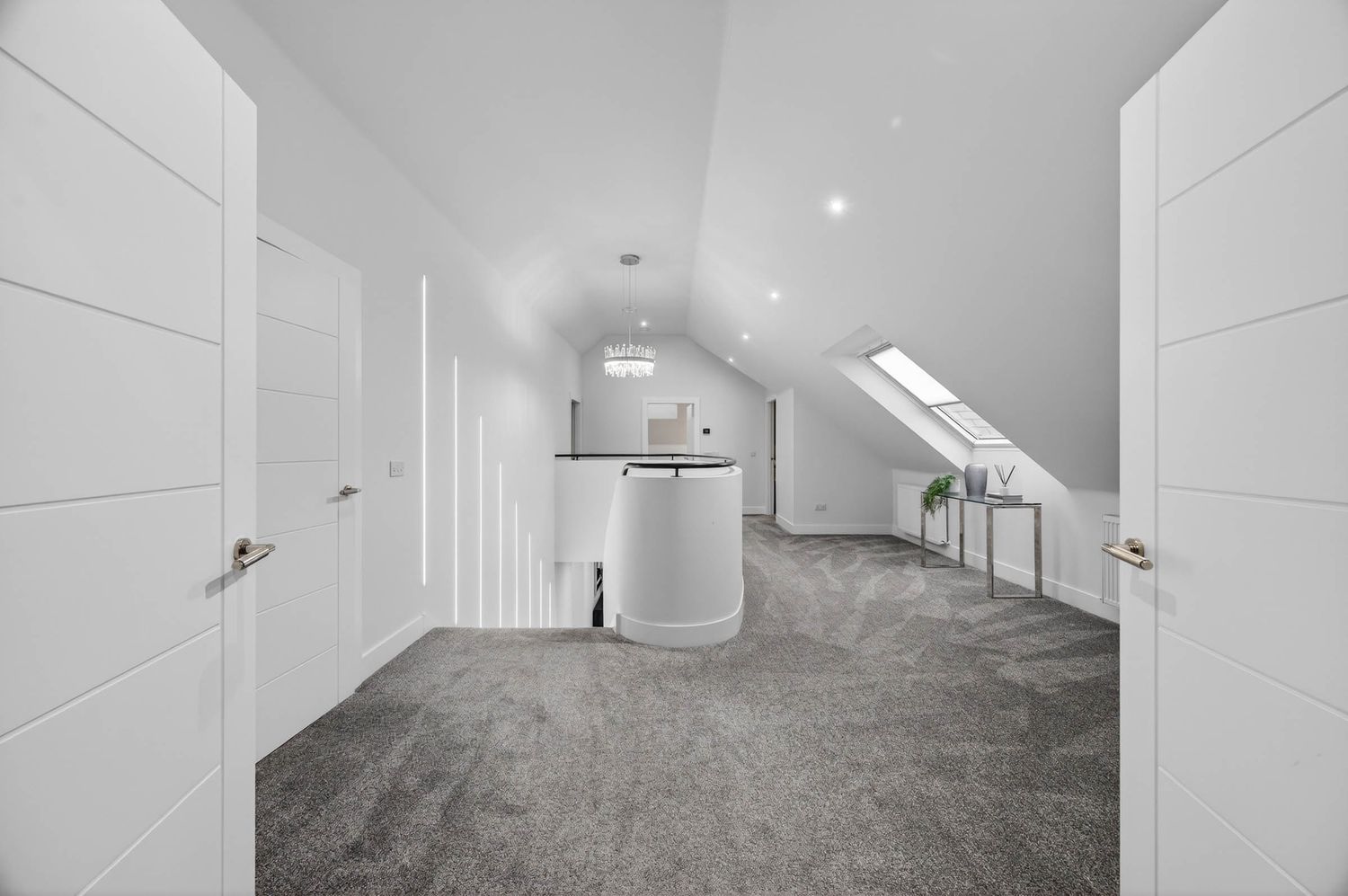 Spacious converted attic hallway with white walls and recessed lighting.