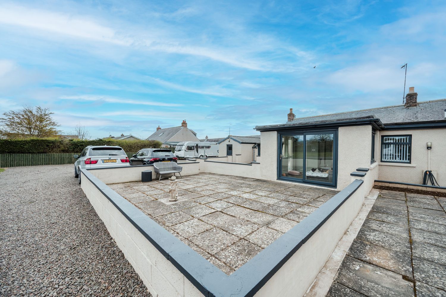 View of modern single-story homes with flat roofs and gravel landscaping under a bright blue sky.
