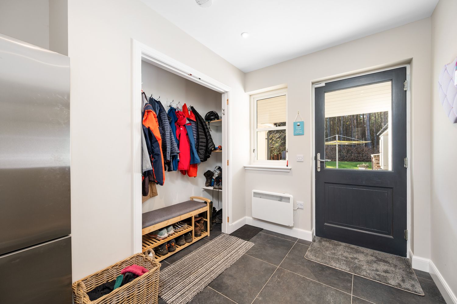 Modern mudroom entryway with built-in storage, coat hooks, and slate tile flooring.