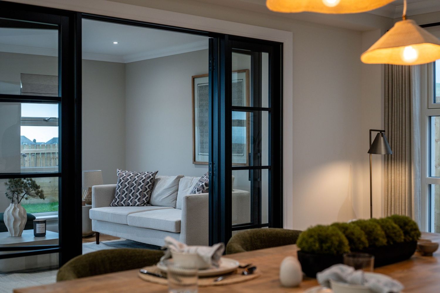 Contemporary living room with black-framed glass doors and comfortable seating arrangements.