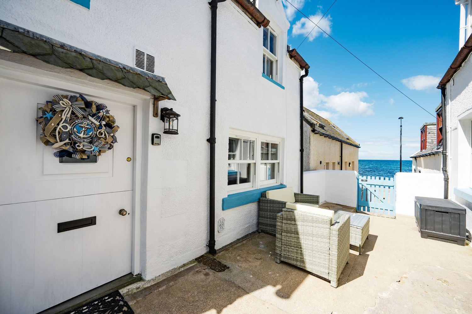 Narrow white alleyways between coastal buildings with traditional architecture and blue skies overhead.
