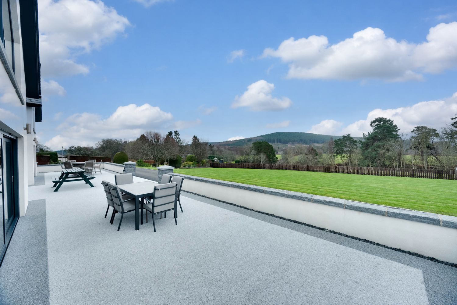A scenic collage of outdoor patio spaces with modern furniture overlooking rolling green hills and countryside views.