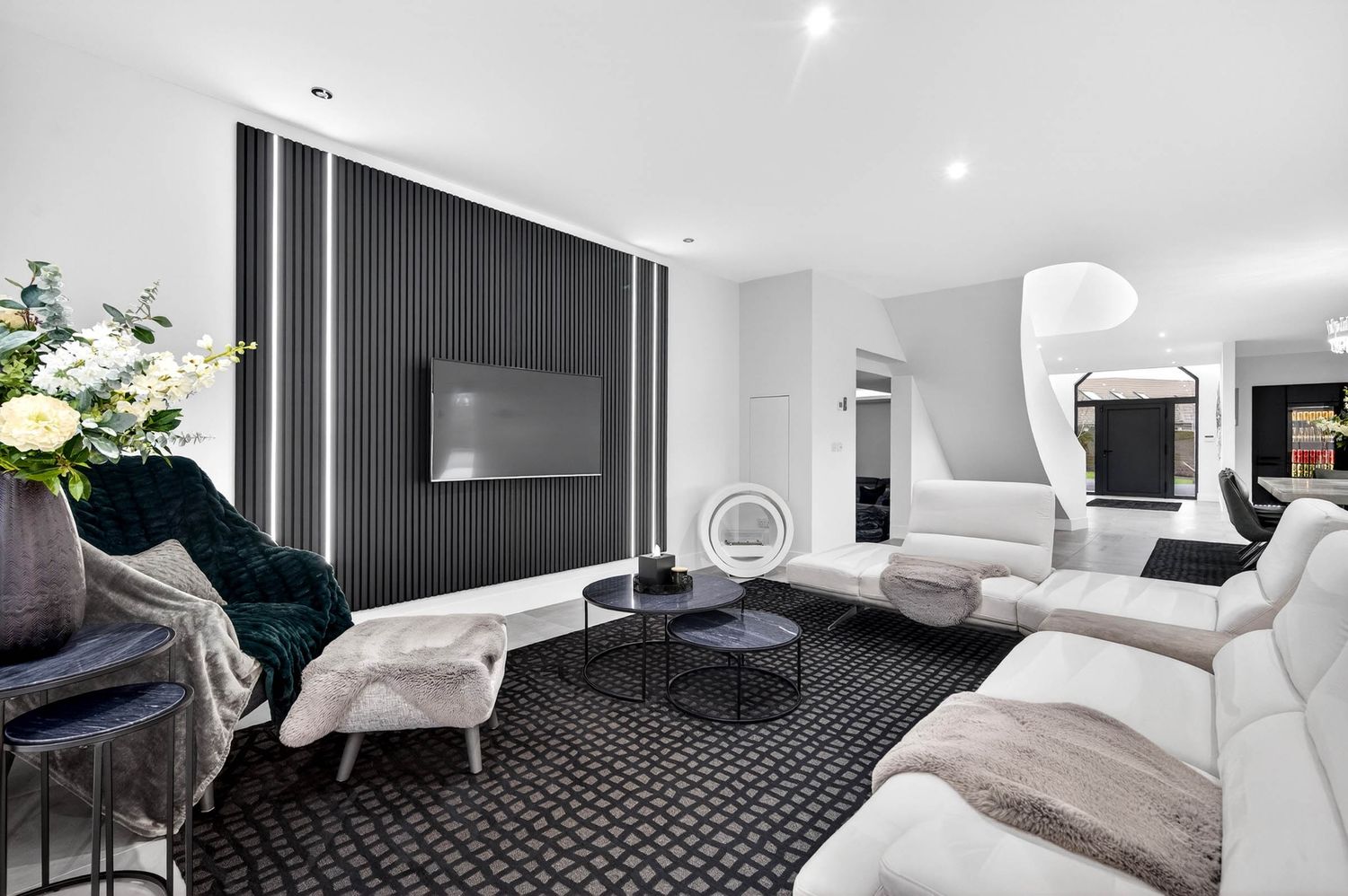 Modern home theater room with white sectional sofa, black accent wall and geometric patterned carpet.