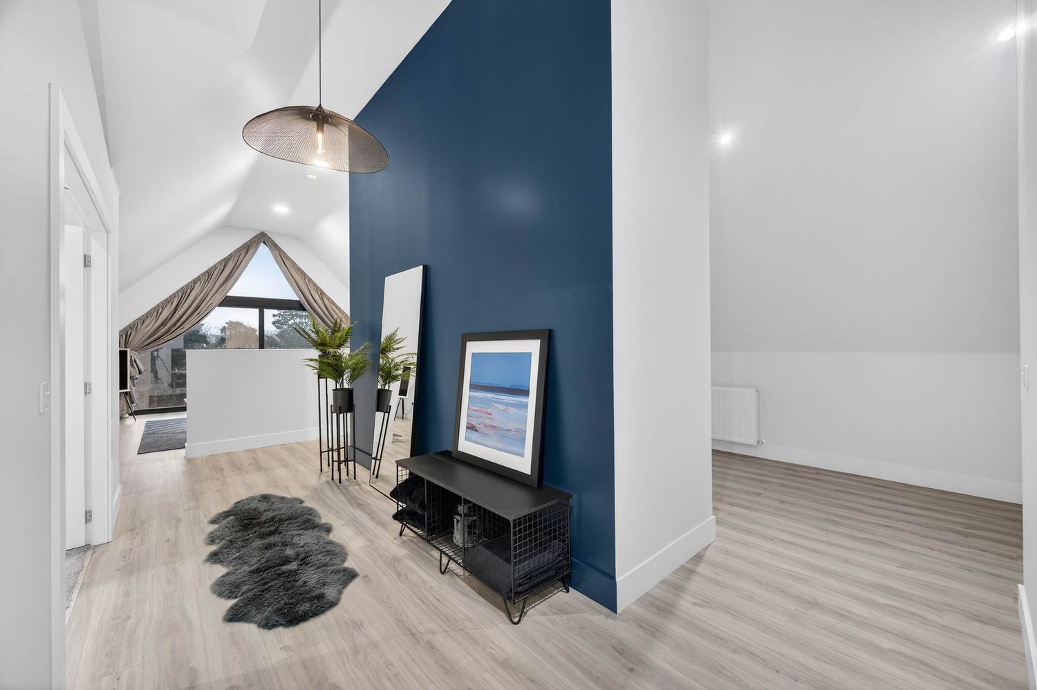 Contemporary attic room with navy accent wall and natural light from skylights.