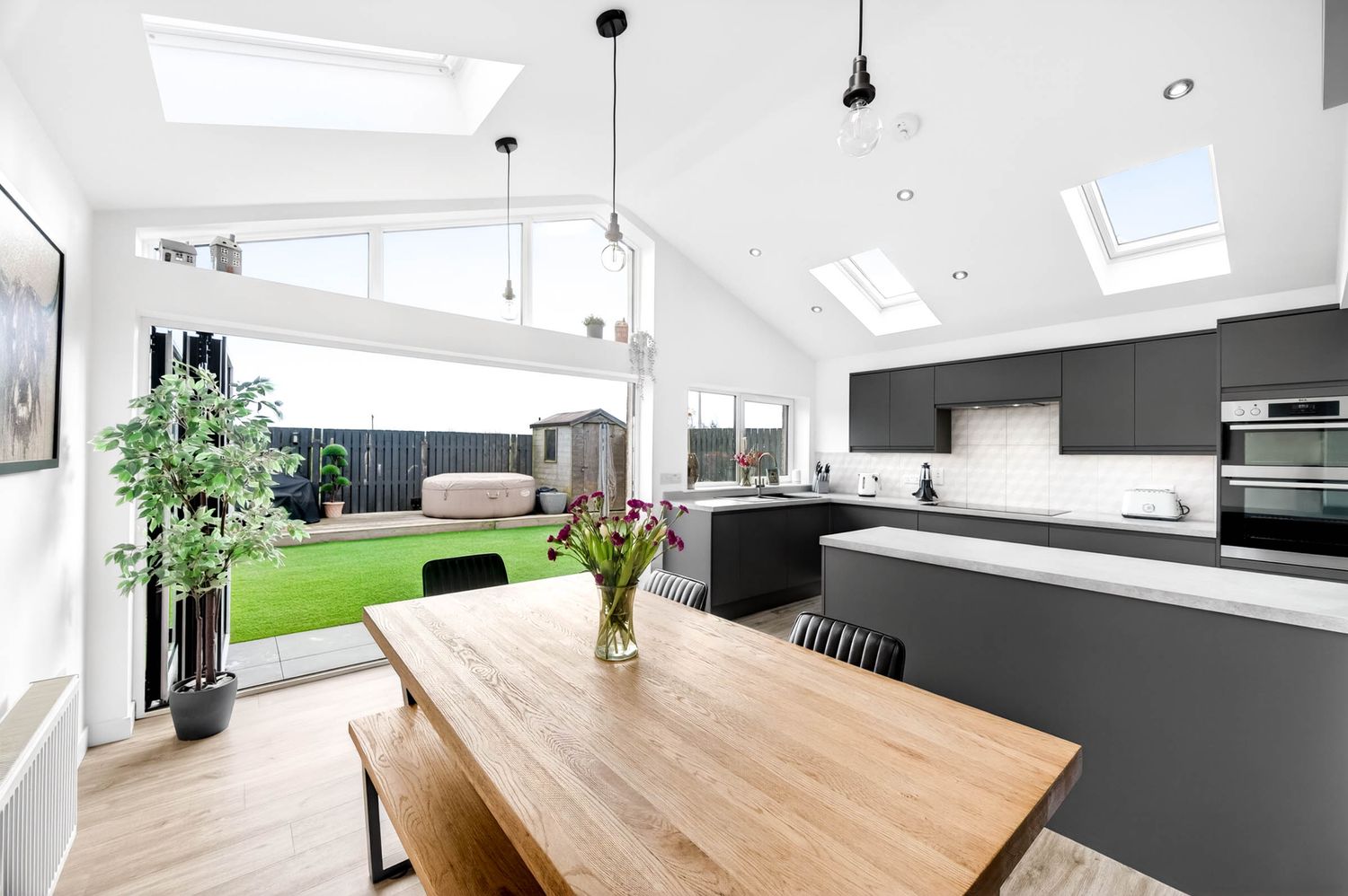 Contemporary dining space with wooden table and natural light from skylights.
