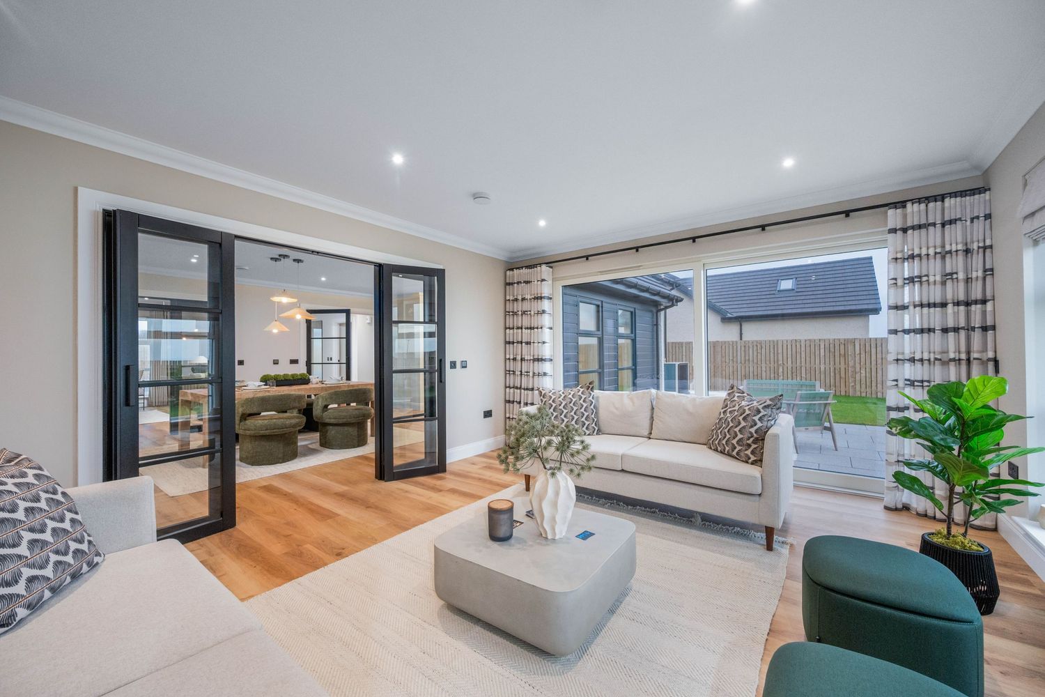 Spacious open-concept living area with white walls and hardwood flooring featuring contemporary furnishings.